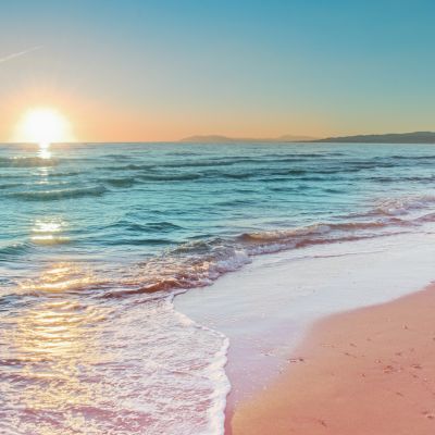 Colorful sunset viewed from the pink sea beach with soft waves